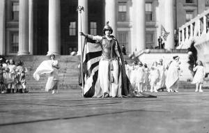 Regal woman in gladiatrix dress leading a women's march